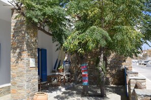 A stone building with a tree in front, a blue shutter, and a colorful cloth hanging on a tree. - Clio's Beach House - Deluxe Beach front property (Ormos Korthiou)