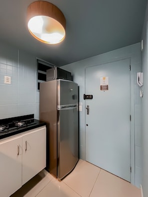 Una cocina moderna con un refrigerador de acero inoxidable, una encimera negra y un armario blanco.