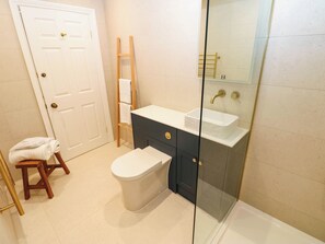 Ein Badezimmer mit Toilette, Waschbecken, einer Duschkabine, einer Holzleiter und einem Handtuchhalter.