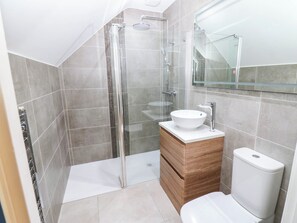 A modern bathroom with a glass-enclosed shower, a white sink, and a toilet. - Bishops Quarter - Flambard (Bishop Auckland)