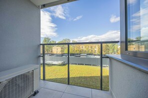Ein Balkon mit Blick auf einen Gebäudekomplex und eine Grünfläche.