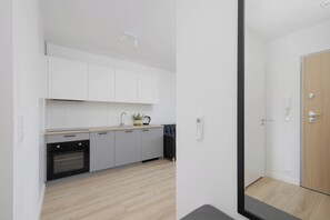 Eine moderne Küche mit weißen Schränken, einem schwarzen Ofen und einer Holzausziehtafel.