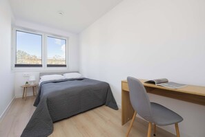 A bedroom with a bed, a desk, a chair, a window, and a view of the outside. - Warsaw | Grenadierów 41 | Modern Apartment | Air Conditioning (Warszawa)