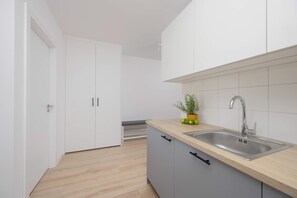 Una cucina moderna con mobili bianchi, un piano di lavoro in legno e un lavello in acciaio inossidabile.