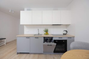 A compact kitchen with white cabinets, a built-in dishwasher, and a black oven. - Warsaw | Grenadierów 41 | Modern Apartment | Air Conditioning (Warszawa)