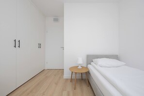 Une pièce minimaliste comprenant un lit, une petite table et une armoire.