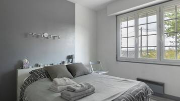Une chambre moderne avec un grand lit, une table de chevet avec une lampe et une fenêtre donnant sur un beau paysage.
