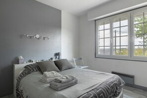 A modern bedroom with a large bed, a bedside table with a lamp, and a window with a view.