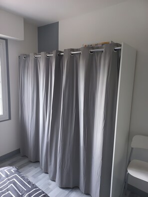 A room with a grey curtain, a bed with a patterned bedspread, and a white chair. - Guest Room 'Laurentine' with Shared Terrace, Shared Garden and Wi-Fi (Montval-sur-Loir)