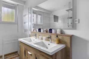 A bathroom with a double sink, wooden vanity, and a large mirror.