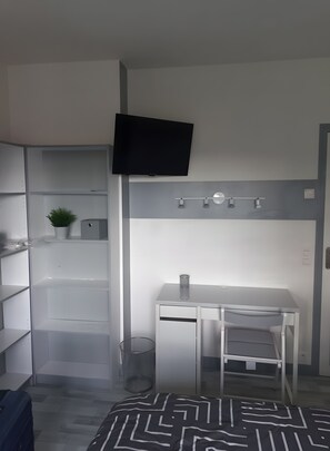 A hotel room with a bed, a desk, a television, and a wardrobe. - Guest Room 'Laurentine' with Shared Terrace, Shared Garden and Wi-Fi (Montval-sur-Loir)