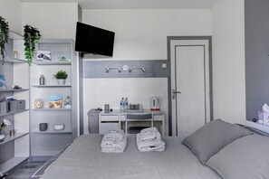 A modern bedroom with a bed, a desk, a chair, a TV, and a wardrobe.