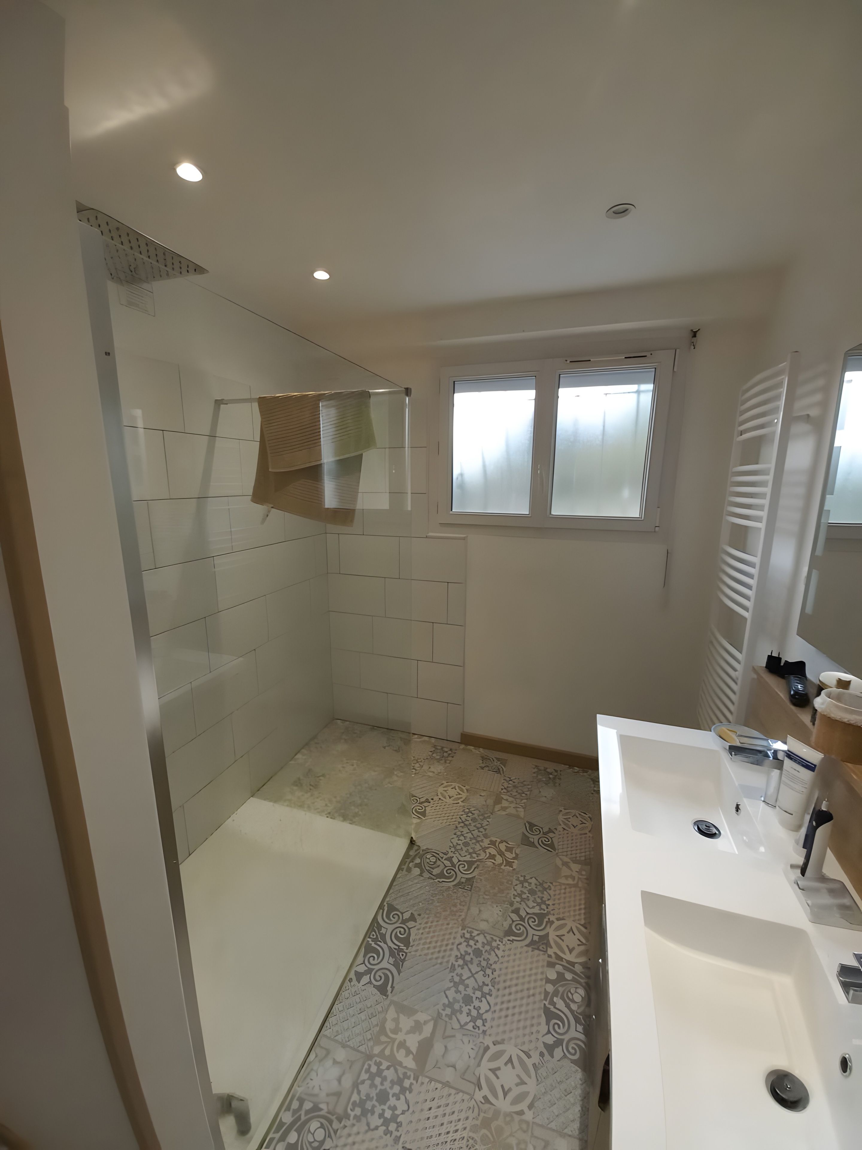 A bathroom with a shower, a sink, and a window.