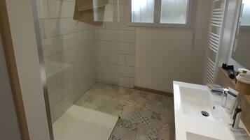 A bathroom with a shower, a sink, and a window.