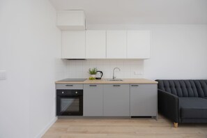 Eine moderne Küche mit grauen Schränken, einem schwarzen Backofen und einer Holzausziehtafel.