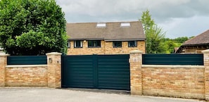 Een tweelaags huis met een bakstenen gevel, een groen metalen hek en een bordje met het nummer 2 op het hek.