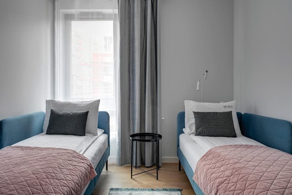 A room with two beds, a small round table, and a window with curtains.