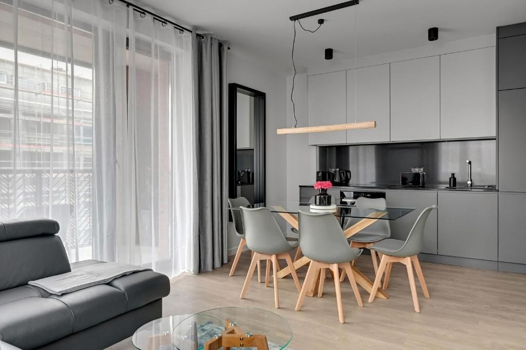 A modern living space with a sofa, dining table, chairs, and a kitchen area.