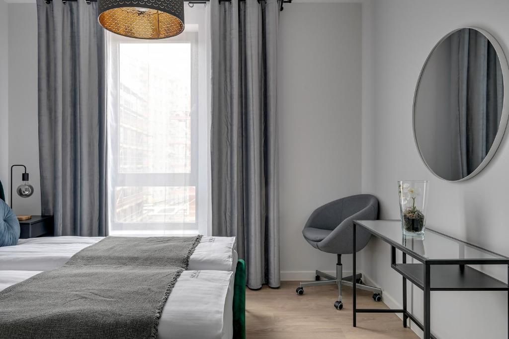 A modern hotel room with a bed, a desk, and a chair.