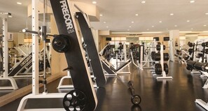 Et fitnesscenter med forskellig træningsudstyr, herunder styrkemaskiner og håndvægte.