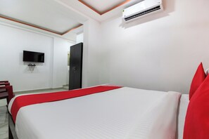 Una habitación de hotel con cama, televisión y aire acondicionado.