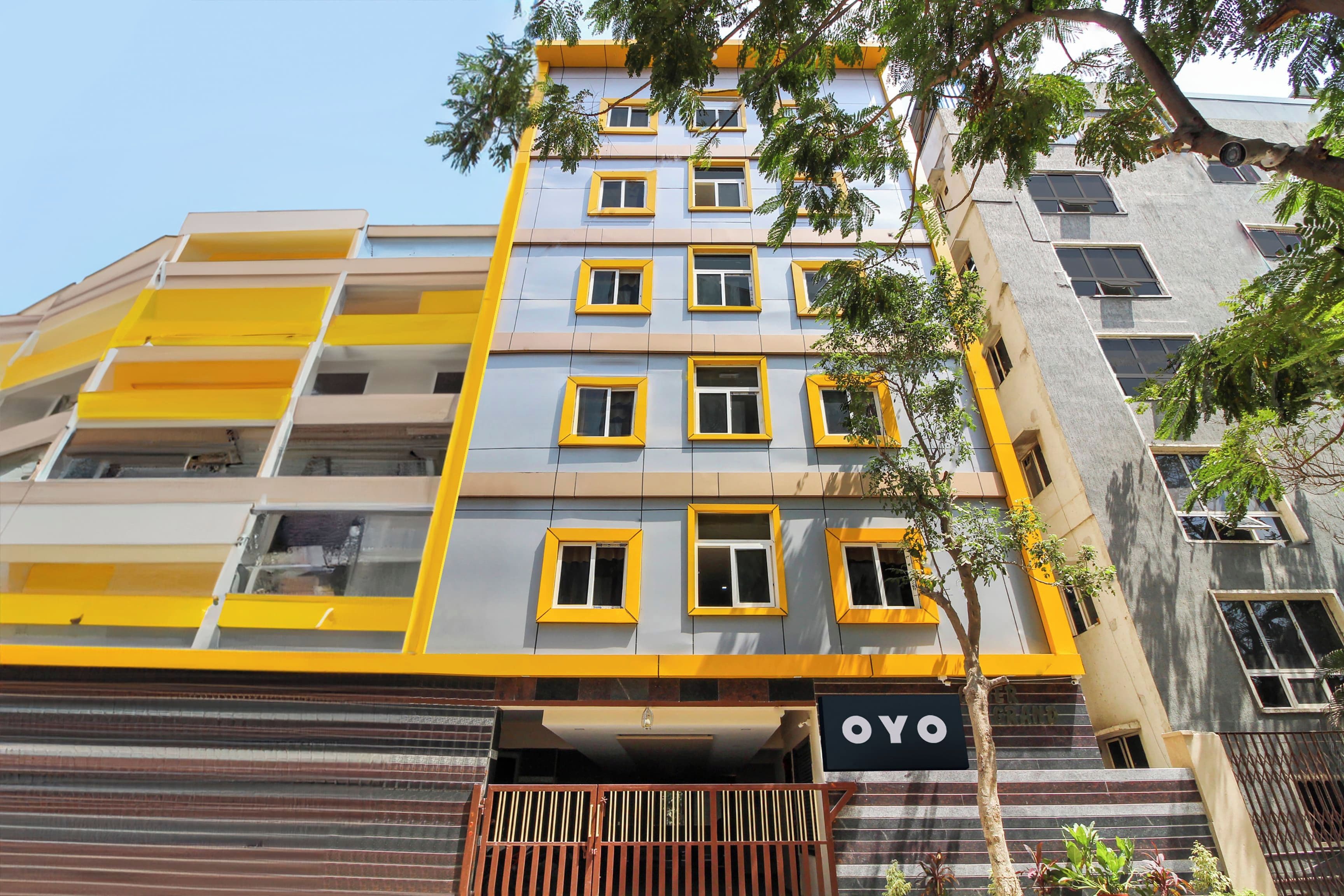 Un edificio de varios pisos con fachada amarilla y gris, múltiples ventanas y un cartel que dice 'OYO'.