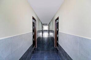 Un pasillo largo y estrecho con suelo de baldosas y puertas a ambos lados.
