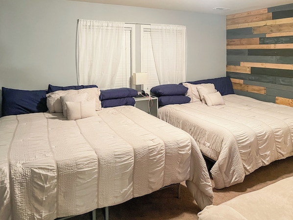 A hotel room with two beds, a nightstand, and a wooden headboard. - 114 - Modern 3BR Home (Gastonia)