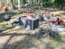 Un área de estar al aire libre con mobiliario de mimbre y una parrilla.
