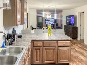 A kitchen with granite countertops, wooden cabinets, a stainless steel sink, a coffee maker, and a decorative vase with lemons. - 114 - Modern 3BR Home (Gastonia)