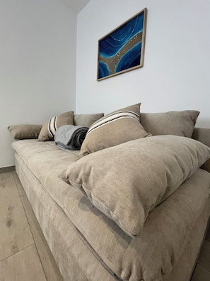 A beige sofa with striped pillows and a blue abstract painting on the wall. - Dimora Estia_Chioggia (Chioggia)