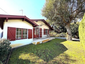 A two-story house with a red door and windows, a small front porch, and a well-maintained lawn. - Villa Gazouillis - Hossegor - Town center - Lake (Soorts-Hossegor)