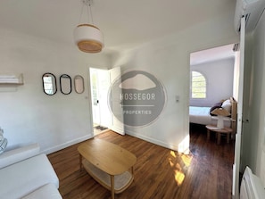 A spacious living room with a wooden floor, a white sofa, a wooden bench, and a hanging light fixture. - Villa Gazouillis - Hossegor - Town center - Lake (Soorts-Hossegor)
