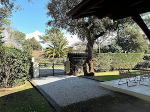 A gated outdoor area with a gravel path, a covered seating area, and a variety of trees and shrubs. - Villa Gazouillis - Hossegor - Town center - Lake (Soorts-Hossegor)