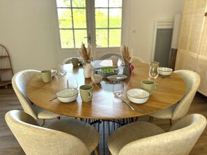 A round dining table with six chairs, a vase with dried plants, and various bowls and cups. - Villa Gazouillis - Hossegor - Town center - Lake (Soorts-Hossegor)