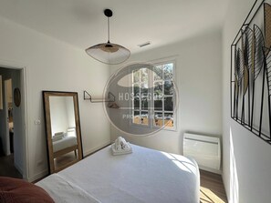Ein Schlafzimmer mit einem großen Bett, einem Spiegel, einem Fenster mit Blick und einer Hängeleuchte.