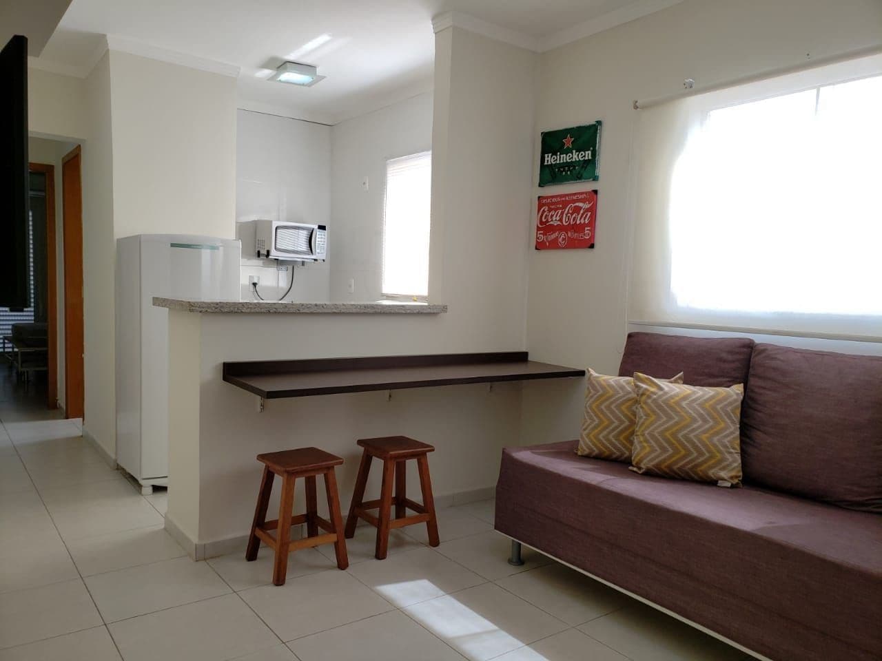 Um espaço compacto com cozinha compacta, sofá e dois banquinhos.