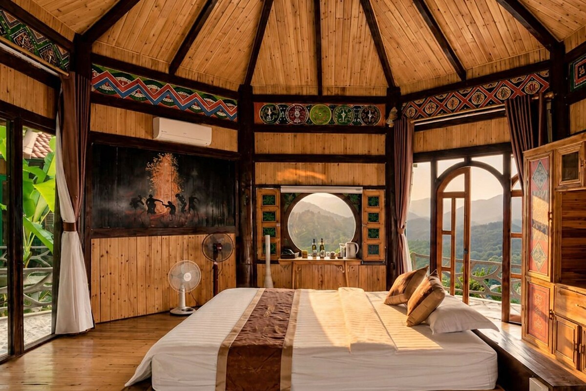 Ein Zimmer mit Holzboden, einem Bett, einem Ventilator und Blick auf Berge.