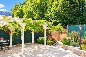 A covered patio area with a pergola, outdoor seating, and a garden with flowering plants. - Large holiday apartment in Wisełka (Wisełka)