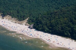 A beach with numerous umbrellas and people, surrounded by dense forest. - Large holiday apartment in Wisełka (Wisełka)
