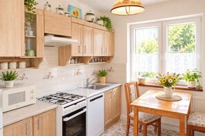 A kitchen with wooden cabinets, a gas stove, a dishwasher, and a dining table with chairs. - Large holiday apartment in Wisełka (Wisełka)