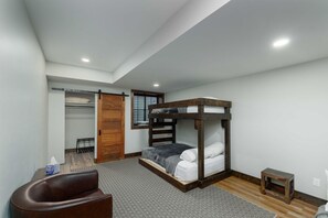 Ein Schlafzimmer mit einem Etagenbett, einem Holzschrank, einem kleinen Tisch und einem Stuhl.