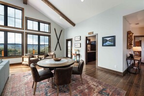 A spacious living area with a round table, comfortable seating, large windows, and a view of the outdoors. - Big Bear Retreat (Gallatin Gateway)