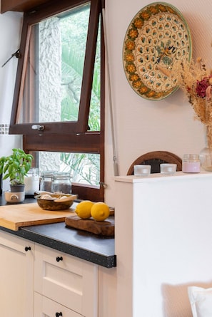 Eine Küche mit Fenster, einem Holztisch zum Schneiden, einer Schüssel und einem Blumentopf.