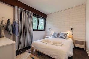 A modern bedroom with a bed, bedside tables, a desk, and a window with curtains. - Appt Bourdaines - Seignosse - Cozy - Beach 2min (Seignosse)