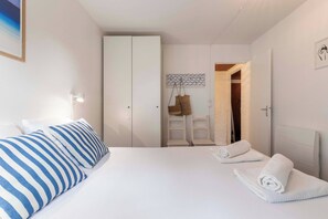 Ein Hotelzimmer mit Bett, Nachttischlampe, Kleiderschrank und einem durch eine offene Tür einsehbaren Badezimmer. Ein Handtuch liegt auf dem Bett.