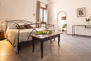 Ein Schlafzimmer mit Bett, Nachttisch, Lampe und Blick auf den Flur.