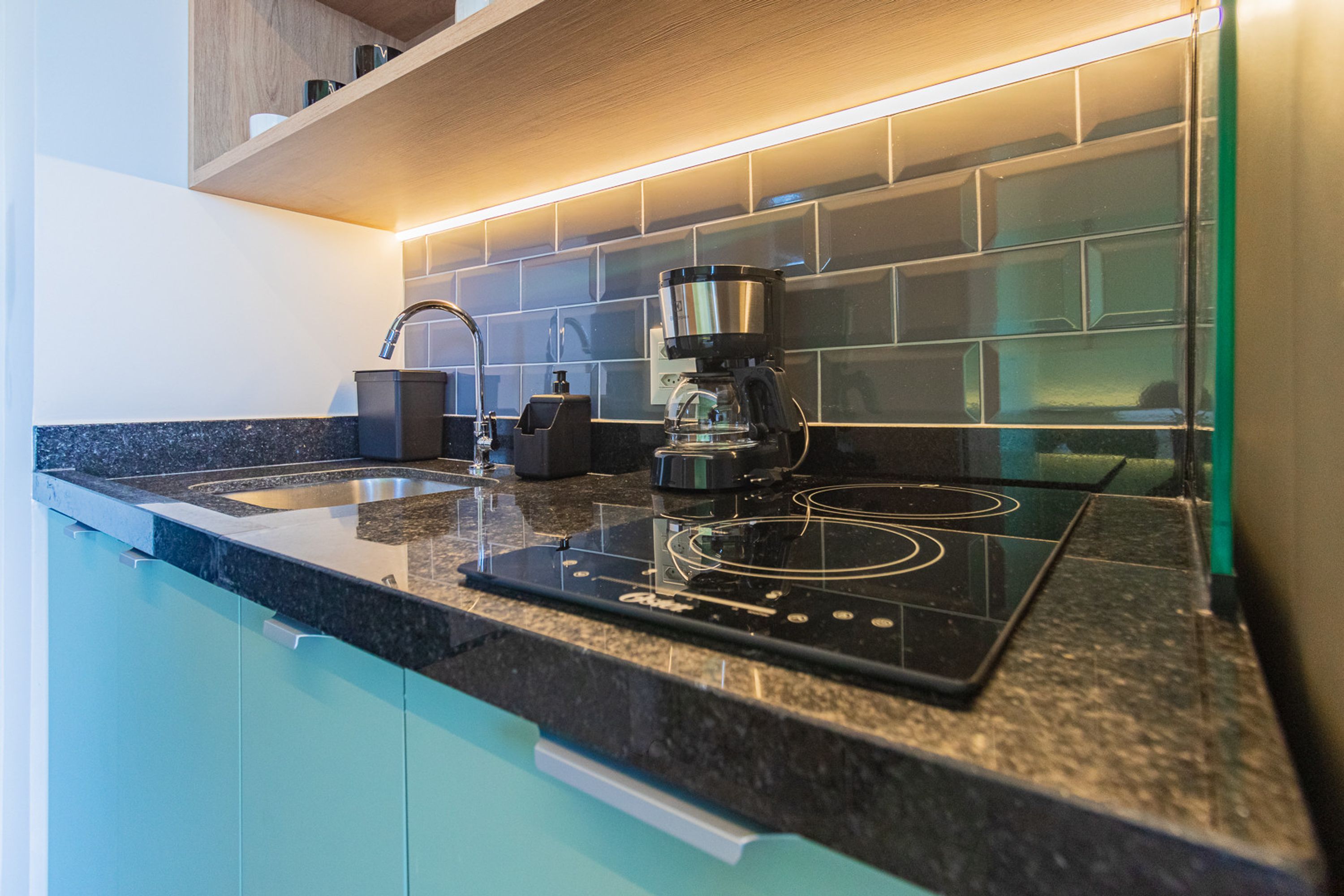 A modern kitchen with a built-in stove, a coffee maker, and a sink.
