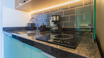 A modern kitchen with a built-in stove, a coffee maker, and a sink.