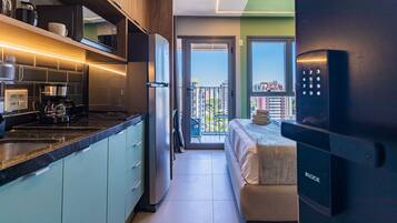 Una cocina moderna con horno empotrado, cafetera y refrigerador. Cuenta con un balcón con vistas a la ciudad.